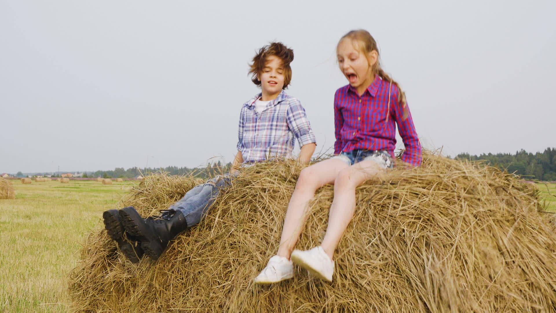 女孩和男孩在农田的干草堆上玩耍视频的预览图