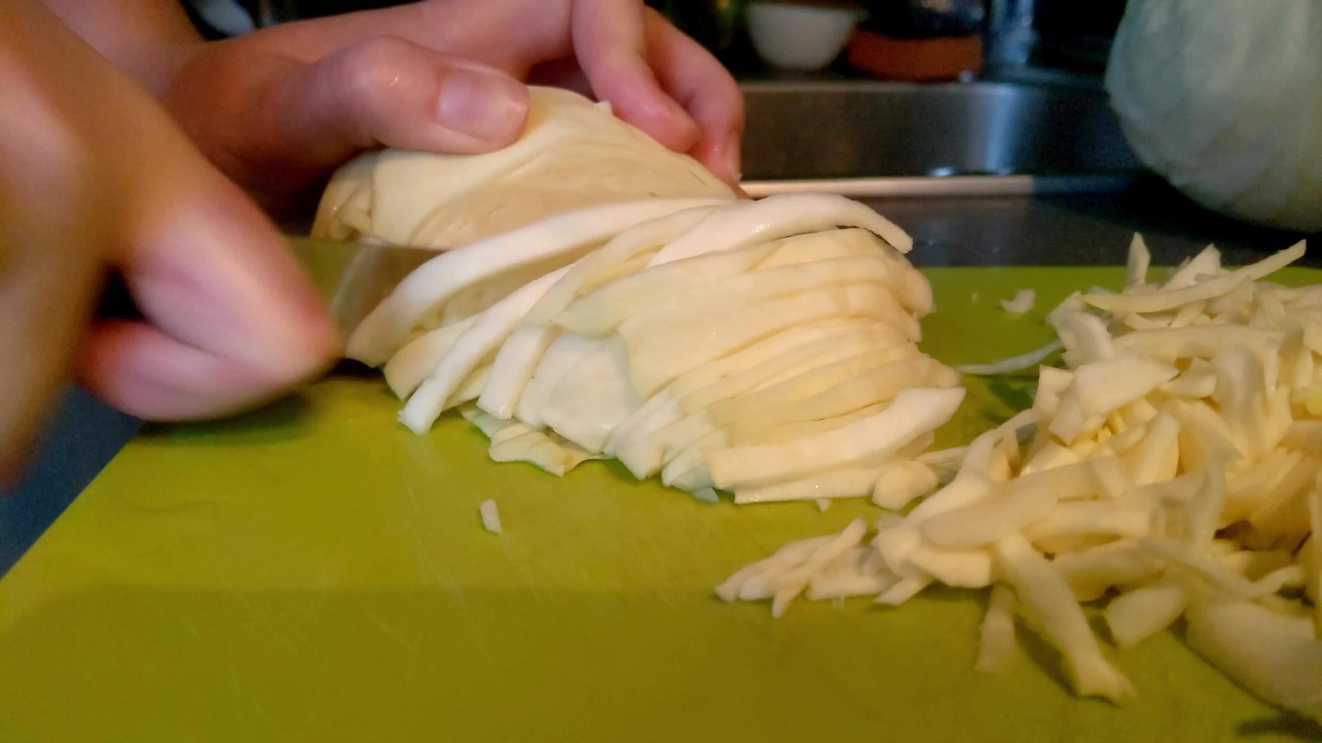 女孩用刀切碎了卷心菜在切割板上视频的预览图