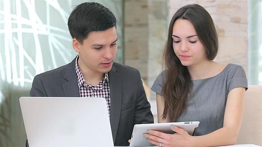 年轻的商人和女人讨论在平板电脑上整理数据视频的预览图