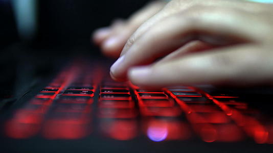 在笔记本电脑上红色键盘上的黑客女孩类型破解密码视频的预览图
