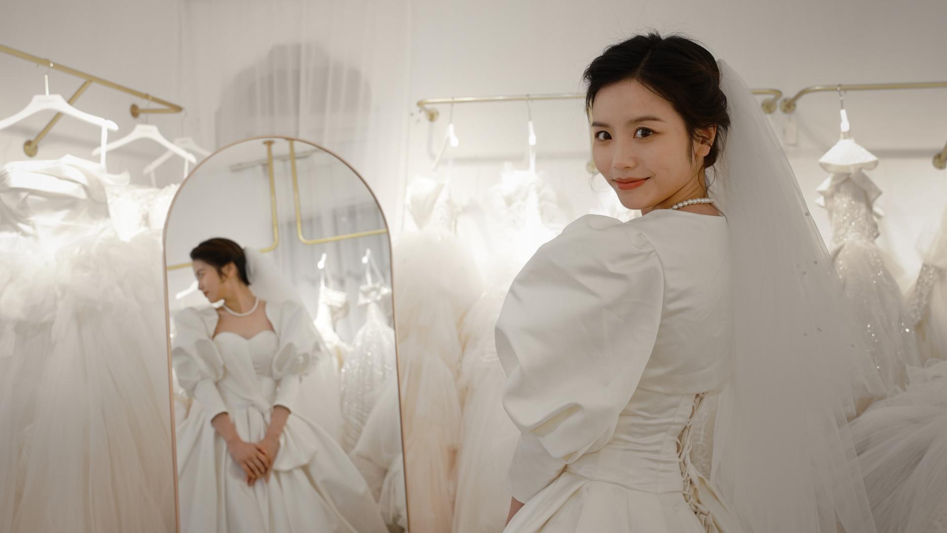 在镜子前试穿婚纱的甜美新娘视频的预览图