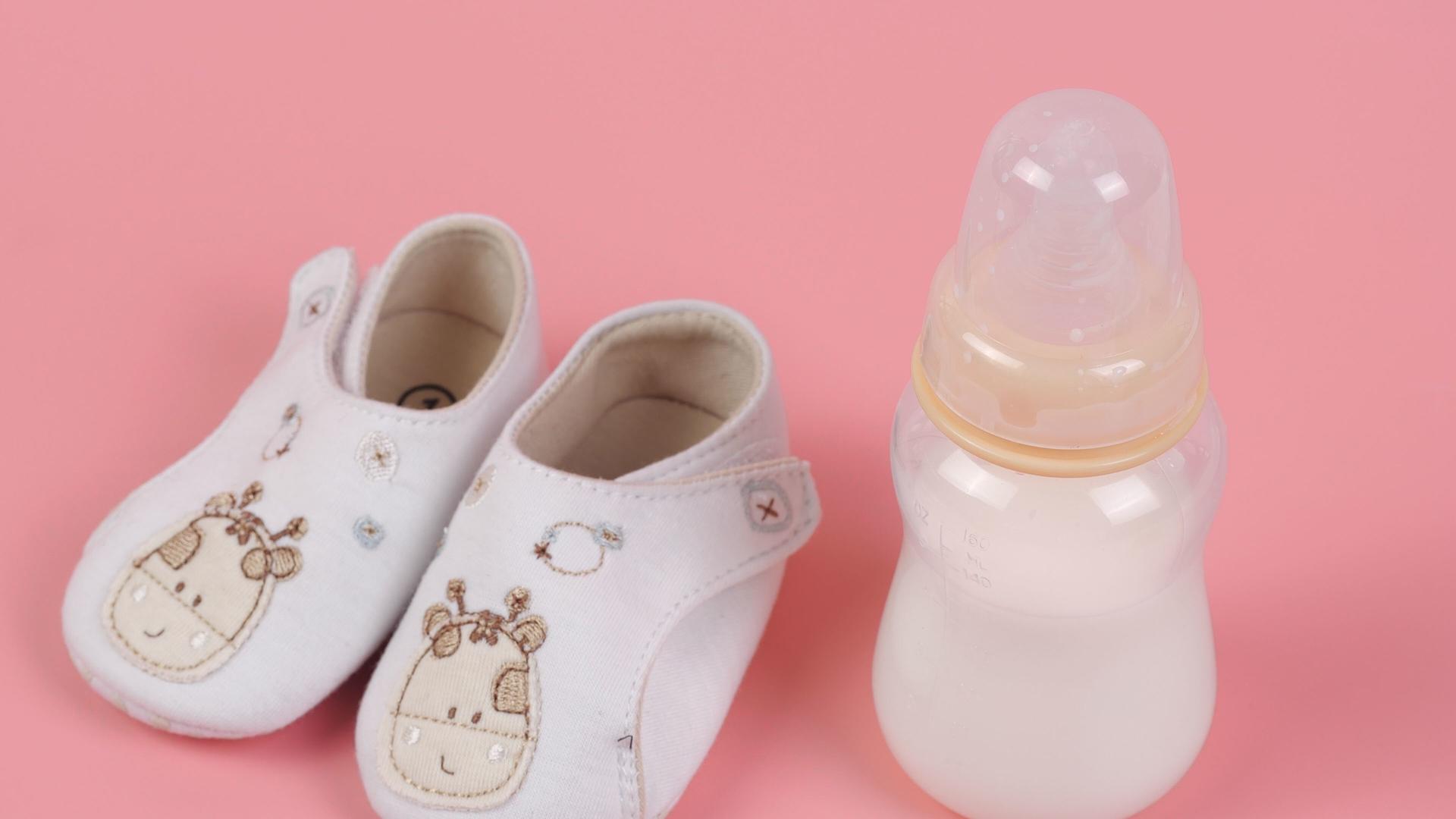粉色背景婴儿鞋和小奶瓶可爱组合视频的预览图
