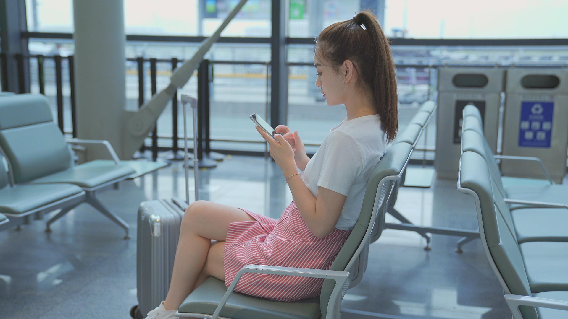 机场候机厅滑手机的女生视频的预览图