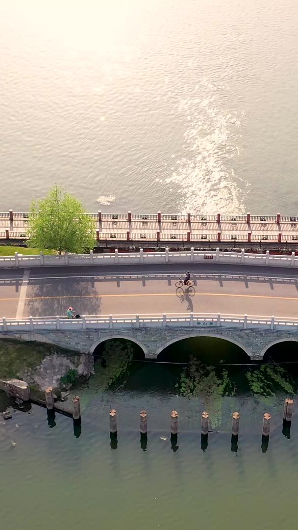 武汉东湖绿道小桥和户外运动员在夕阳下航拍视频的预览图