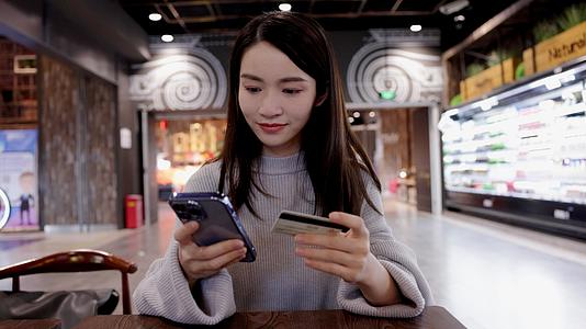 商场用手机输入银行卡号的女青年视频的预览图