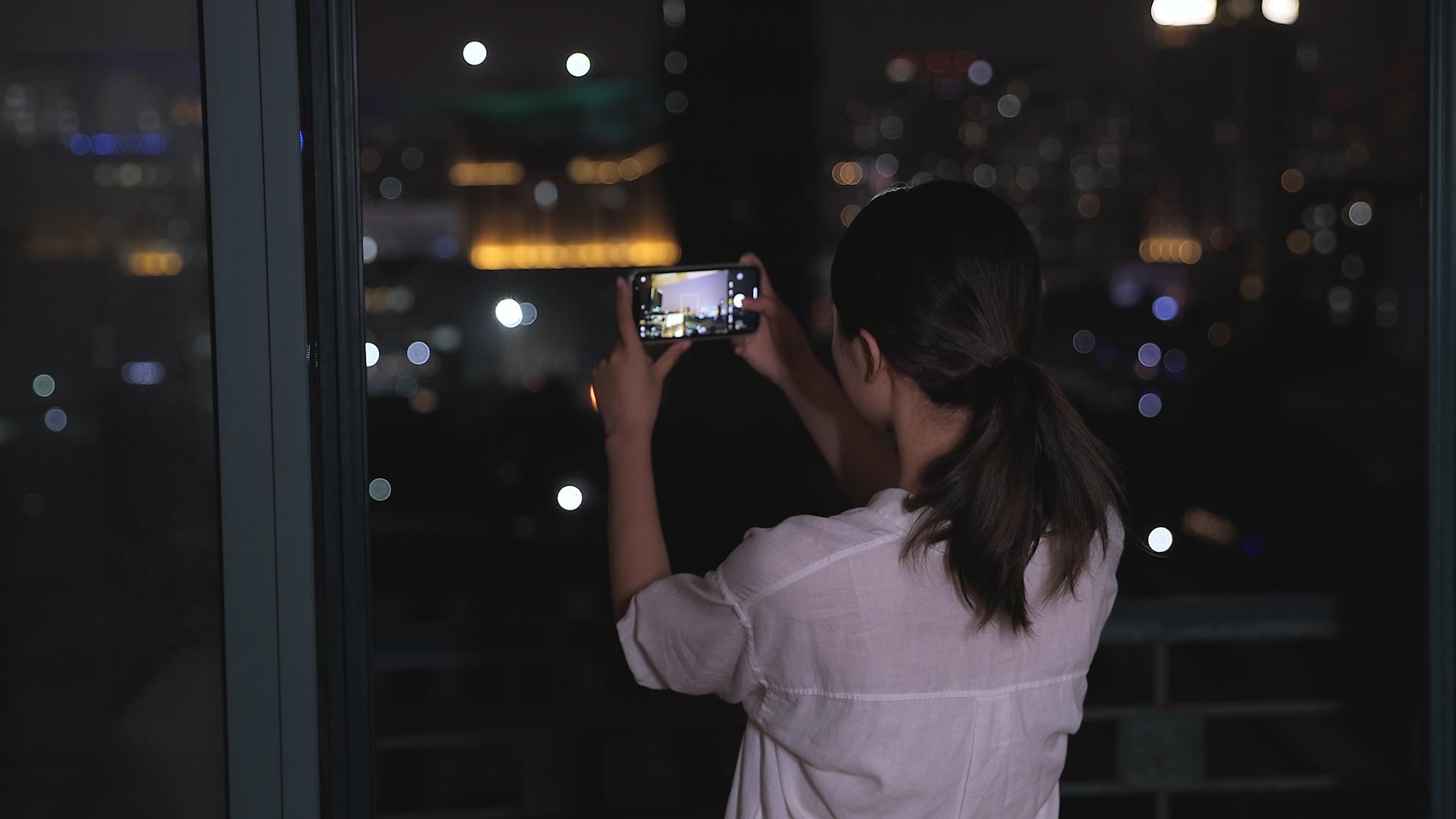 夜晚女性用手机拍照视频的预览图