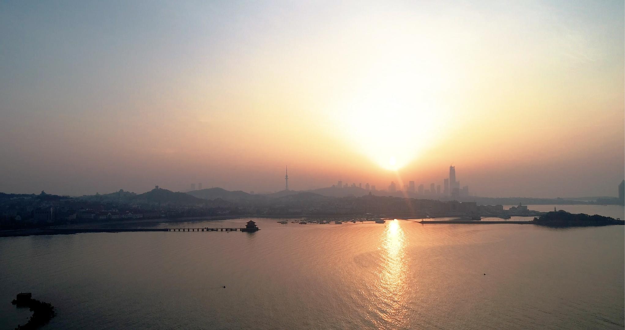 航拍日出时的城市剪影和金光闪闪的海面视频的预览图
