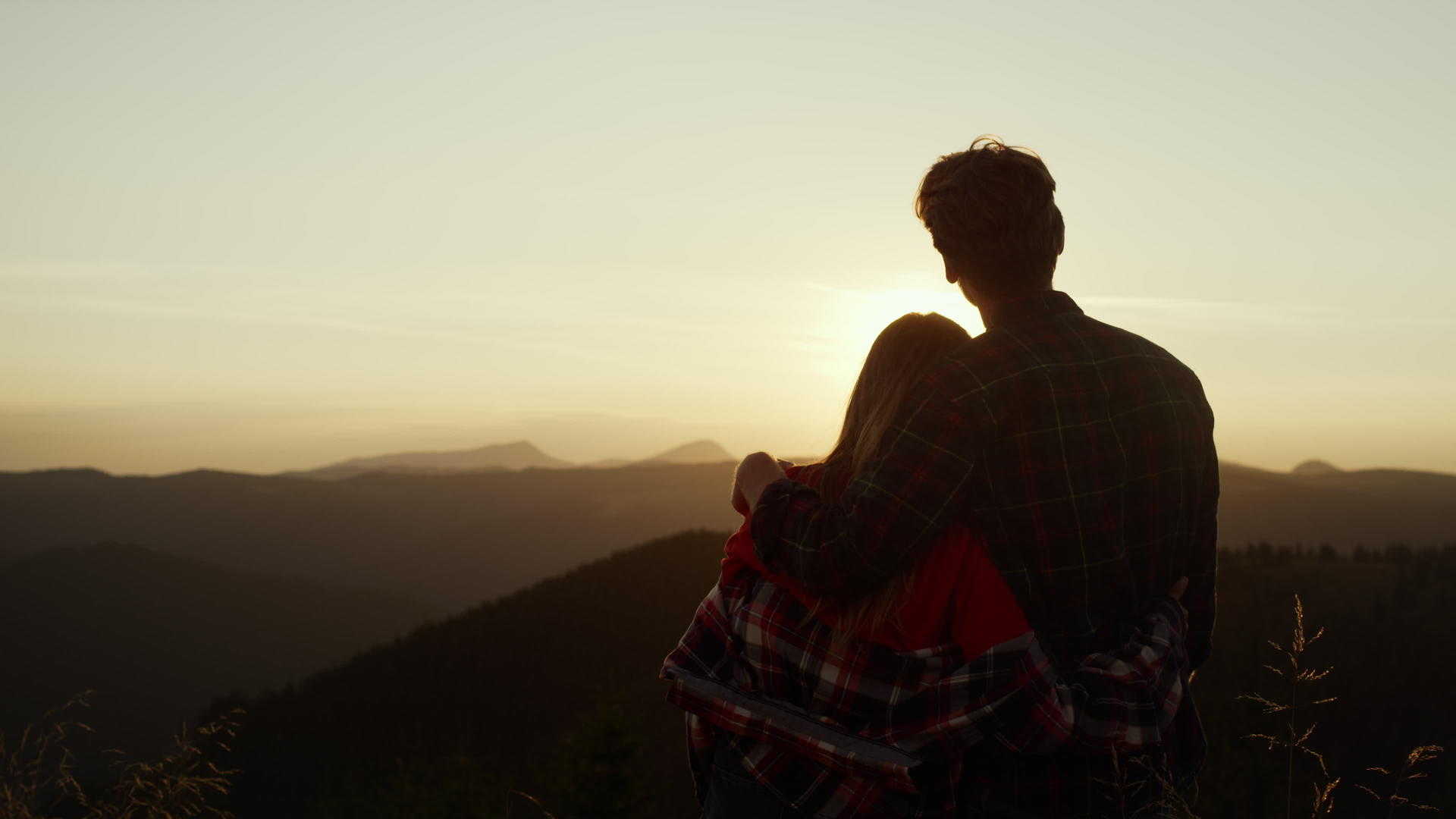 情侣们站在山顶上依偎在一起看日落剪影视频的预览图