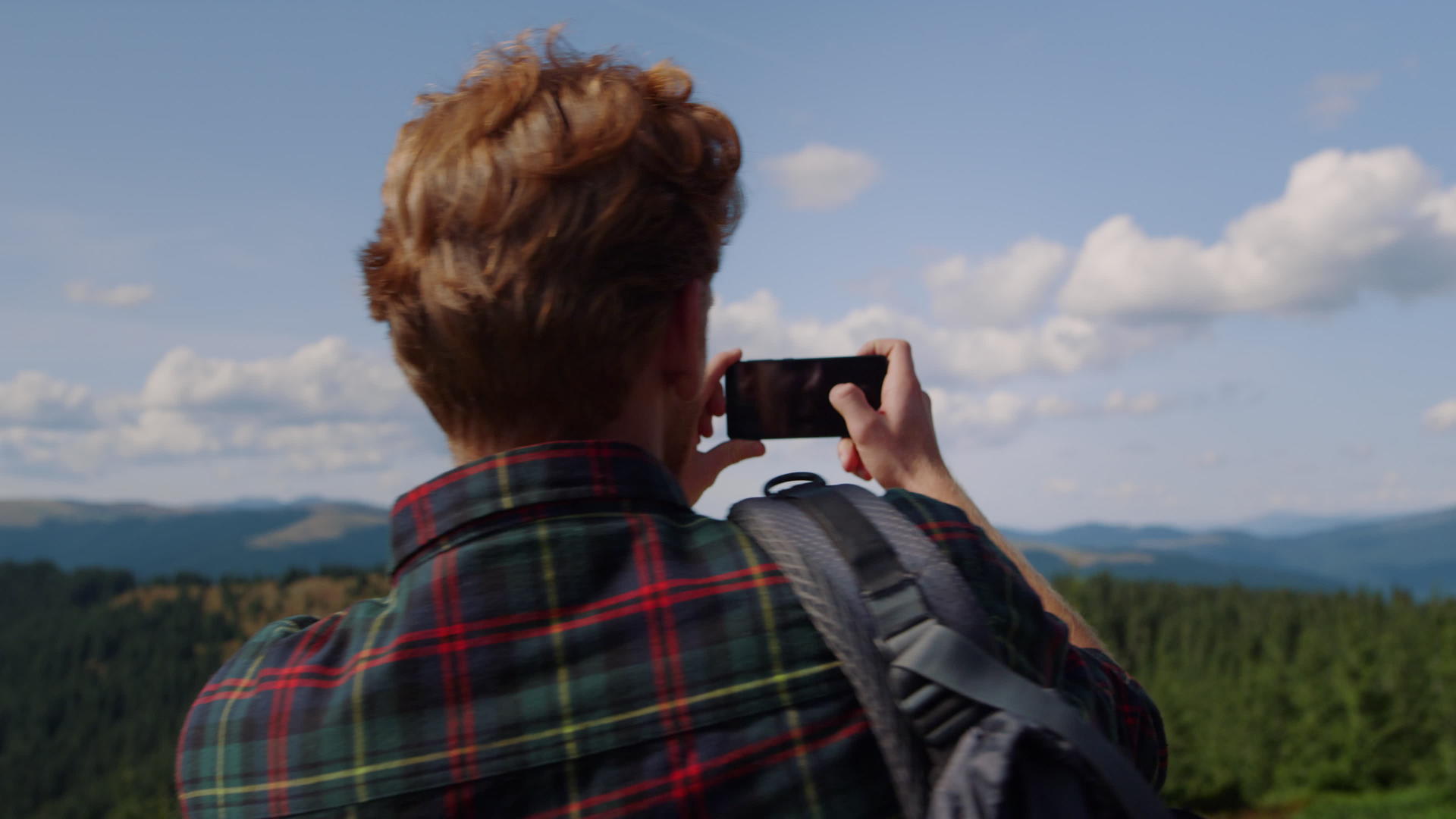 年轻人在山顶用手机拍摄自然风光视频的预览图
