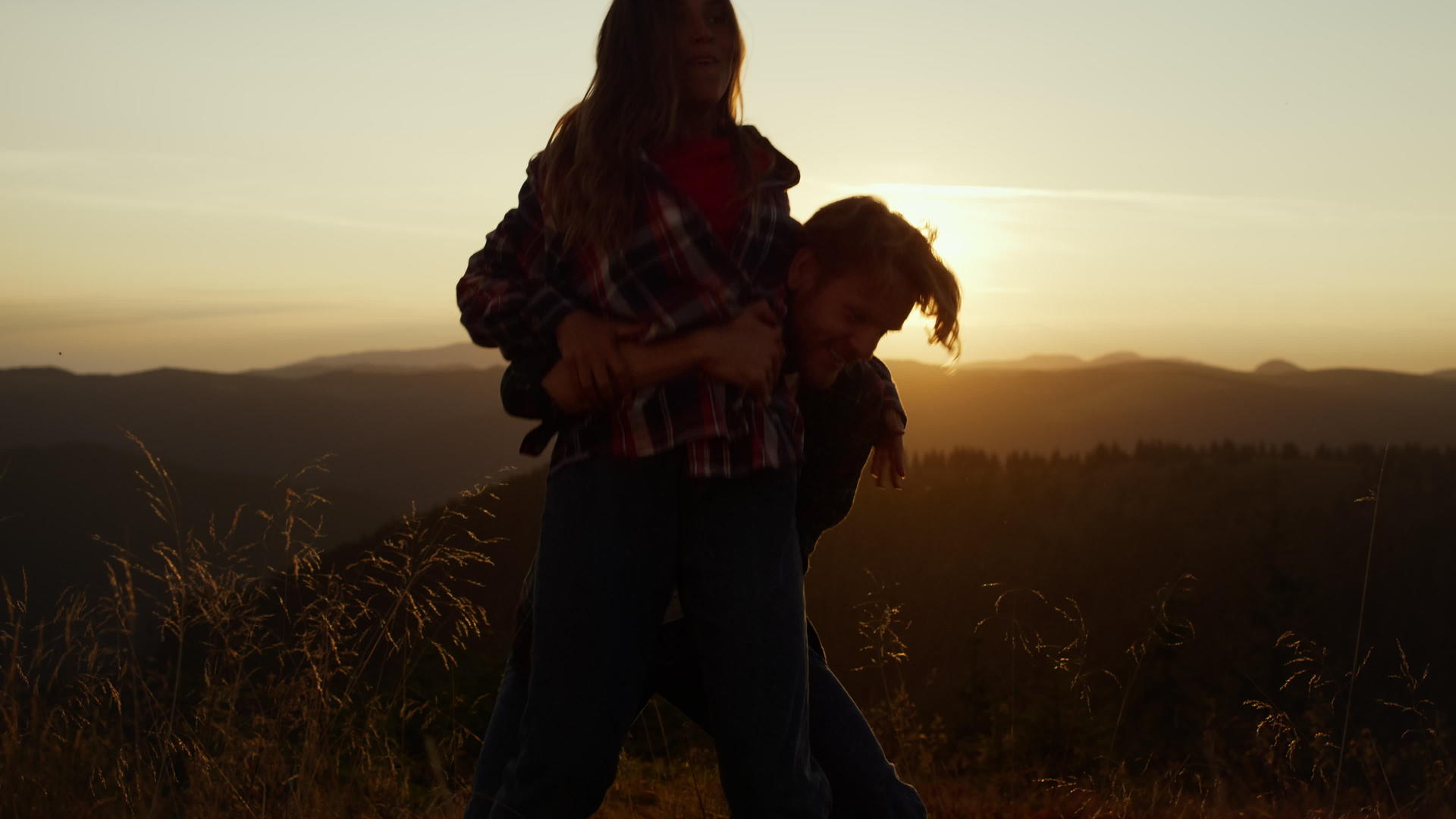 在山顶上互相玩耍的情侣的日落剪影视频的预览图