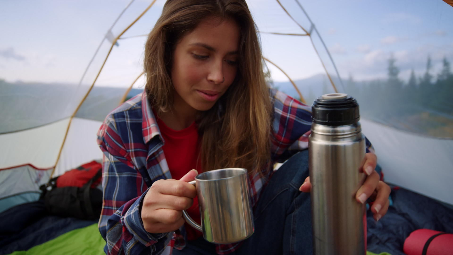 山顶露营在帐篷里女人倒热水喝水视频的预览图