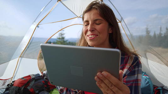 山顶露营在帐篷里女人用平板电脑视频通话视频的预览图
