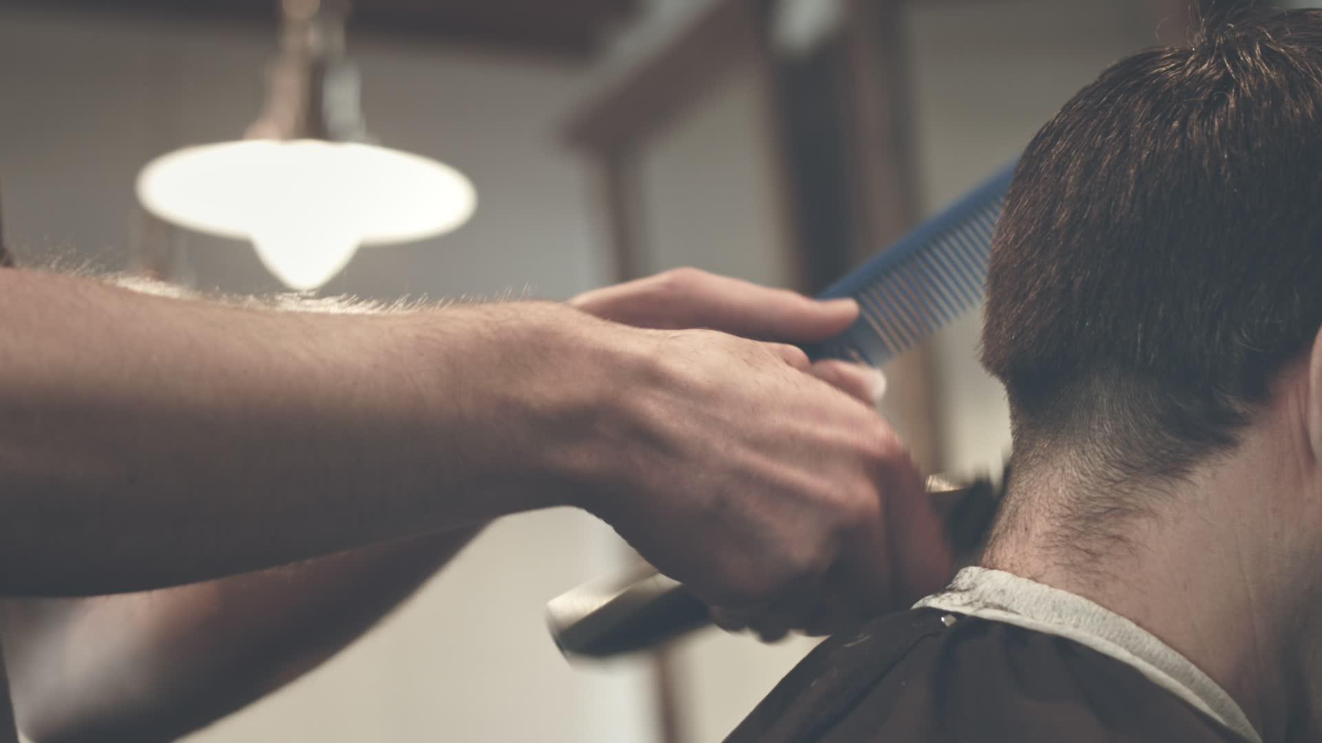 理发师的第一个视角是修剪男性顾客的头发视频的预览图