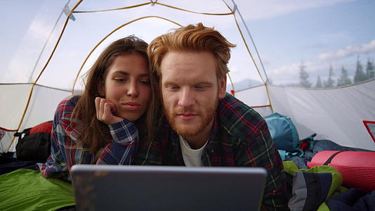 山顶露营帐篷里有平板追剧的情侣视频的预览图