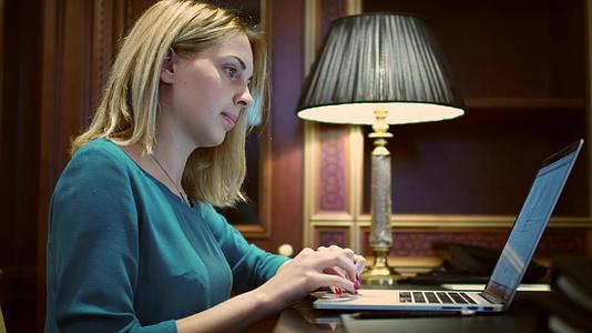年轻女性在桌子前打开笔记本电脑认真工作视频的预览图