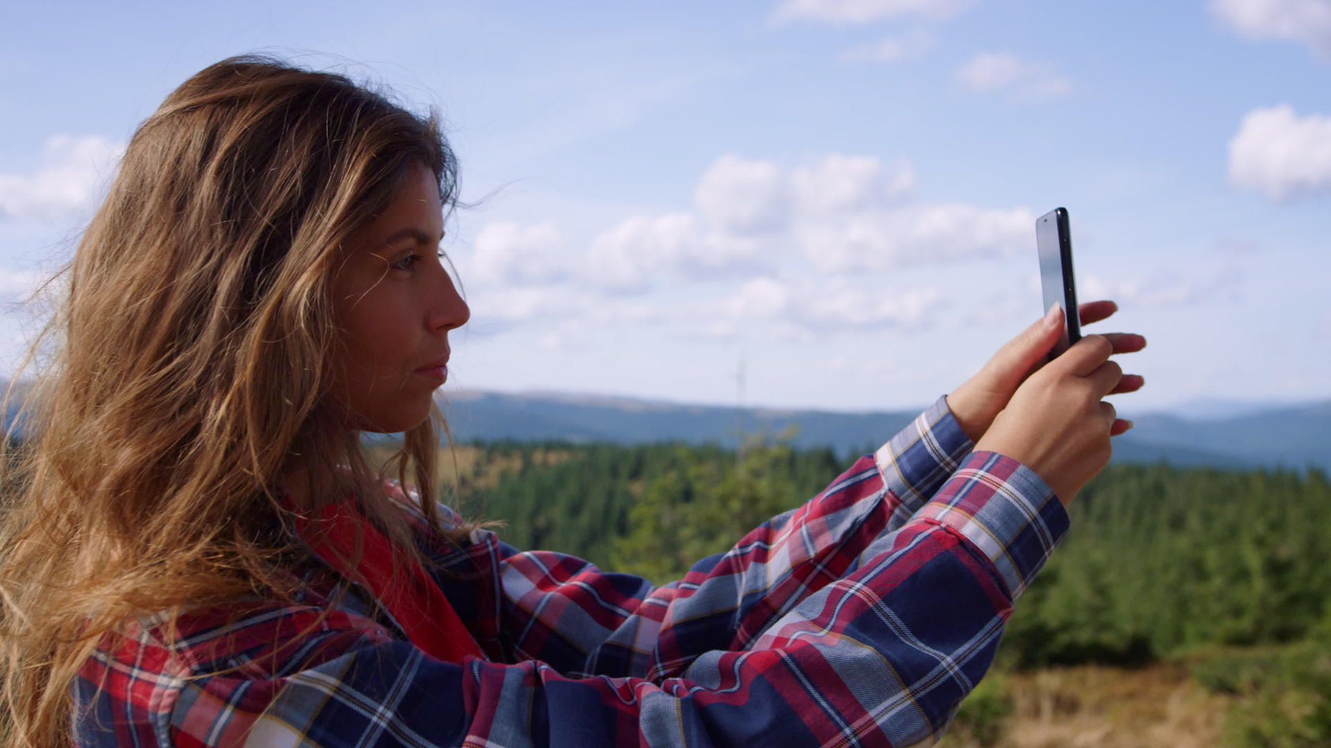 山顶上的女孩用手机拍照视频的预览图
