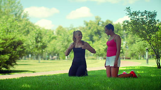 两个女孩在草坪上做瑜伽准备视频的预览图