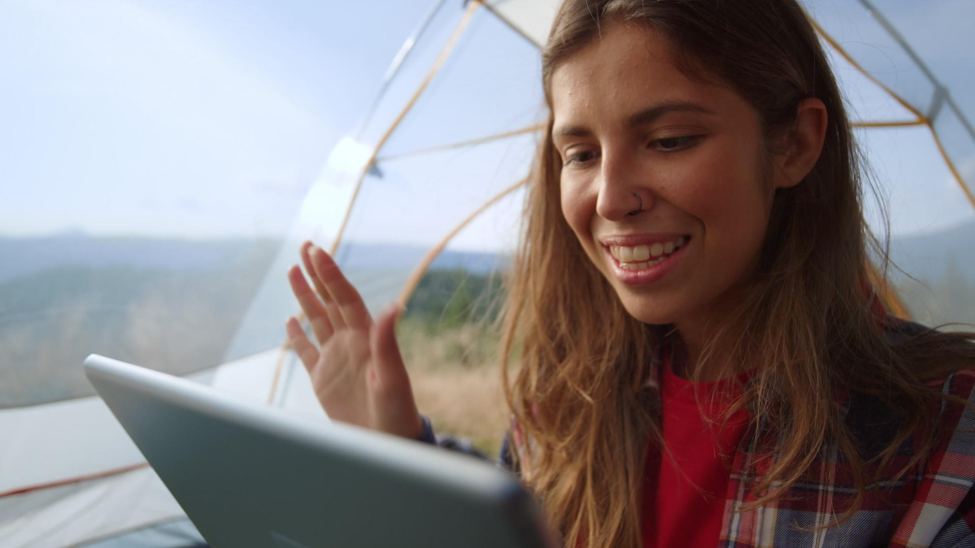 女孩在户外露营时搭起帐篷ipad视频聊天视频的预览图