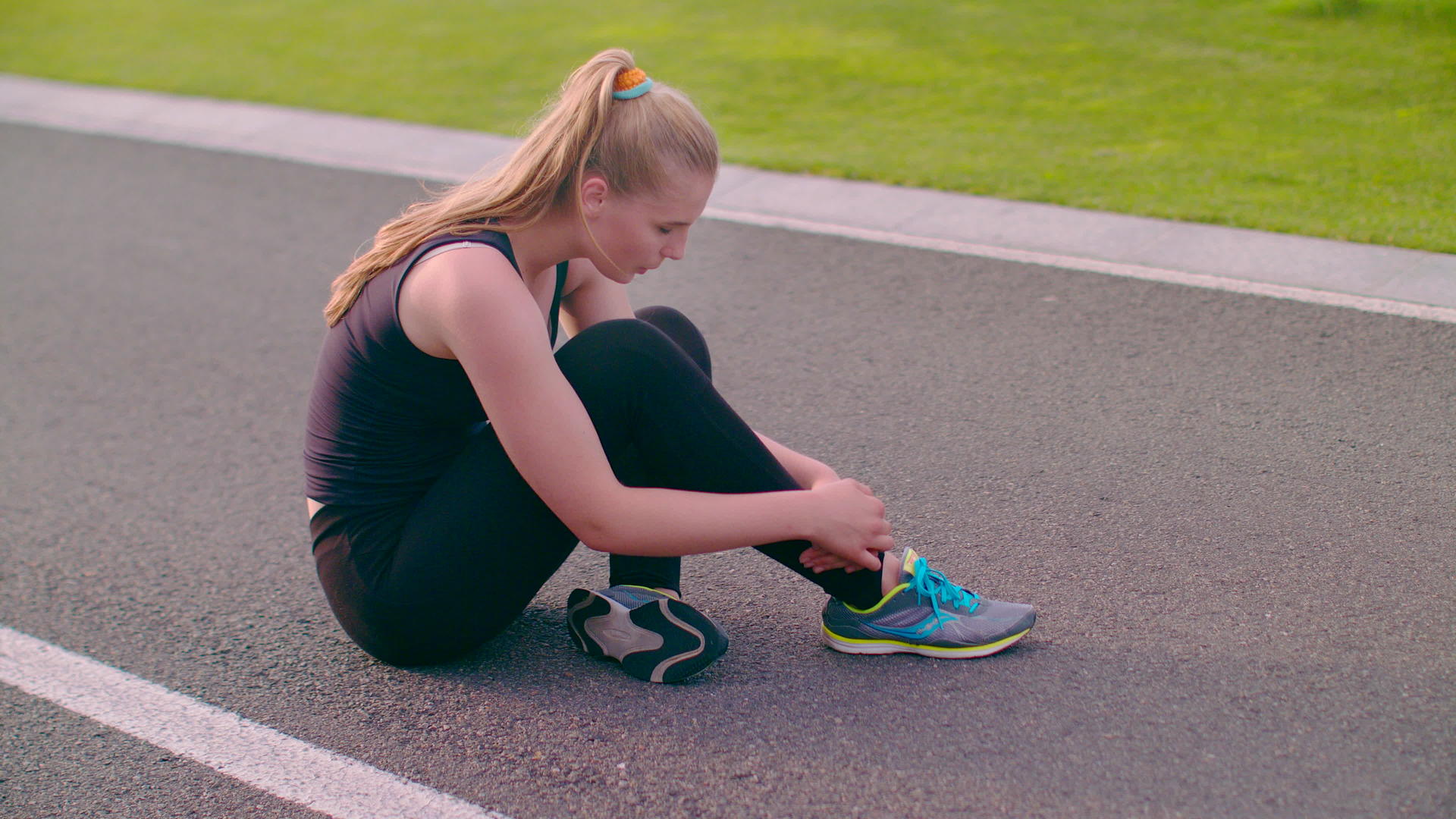 女性在塑胶跑道上系鞋带视频的预览图