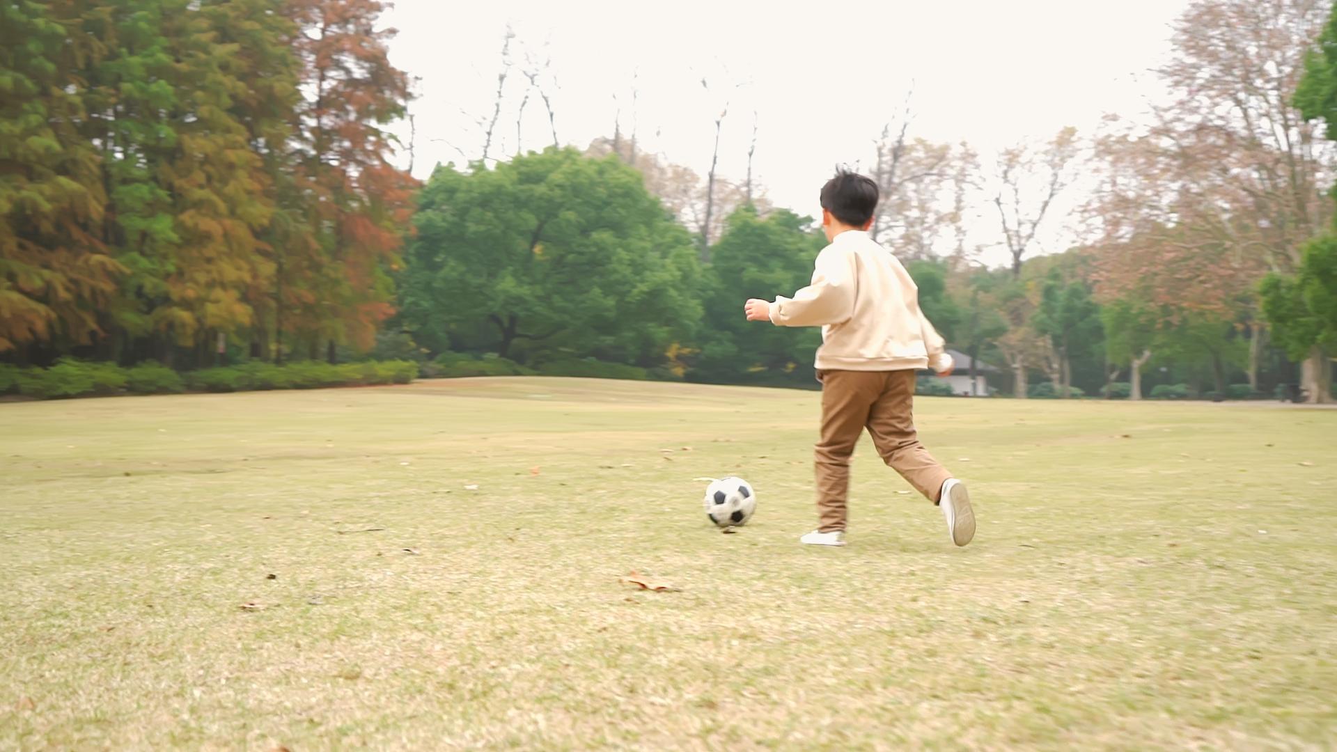 户外小男孩在草地上踢球背影升格视频视频的预览图