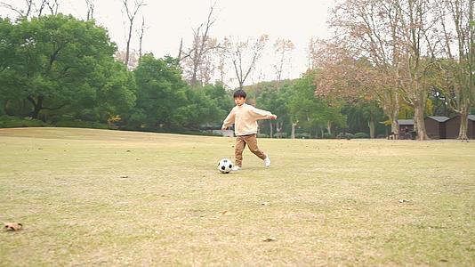 秋季小男孩在公园里踢足球升格视频视频的预览图