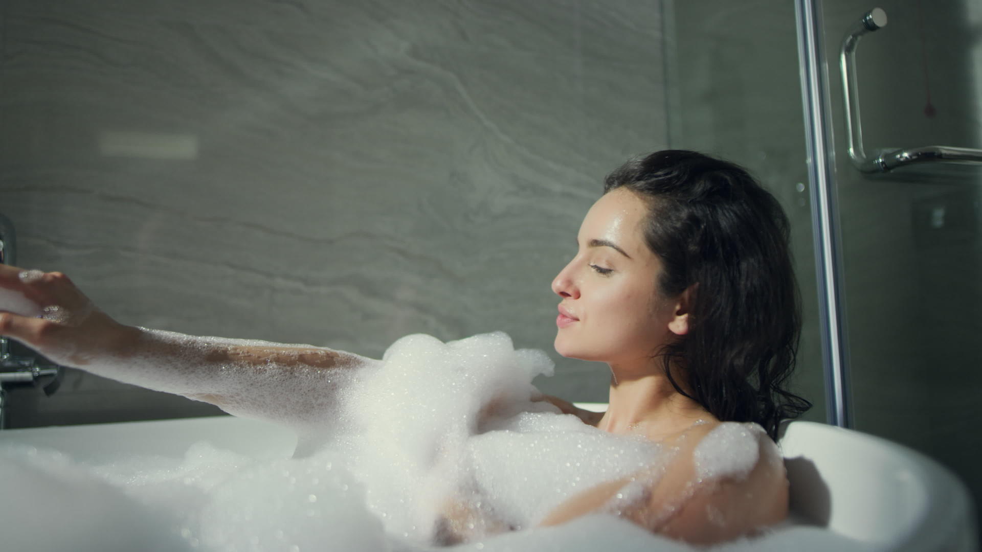 可爱的女人躺在浴缸里泡泡浴视频的预览图
