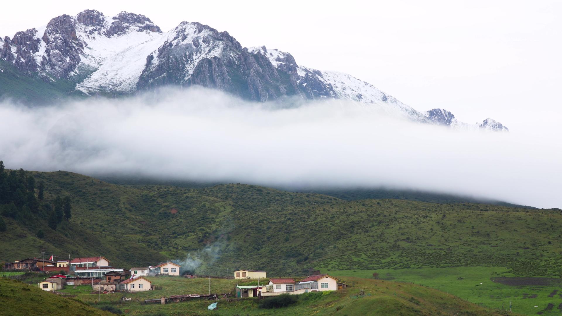 云雾缭绕的雪山脚下小村庄延时视频视频的预览图
