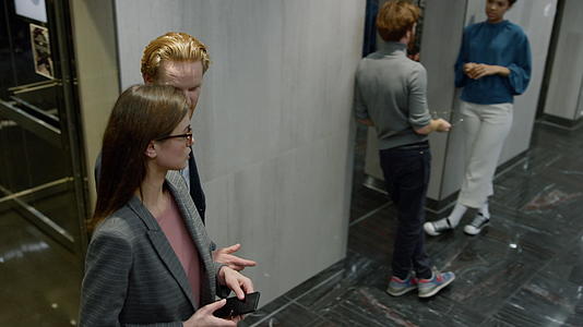 商务人士和女性在电梯车上交谈视频的预览图