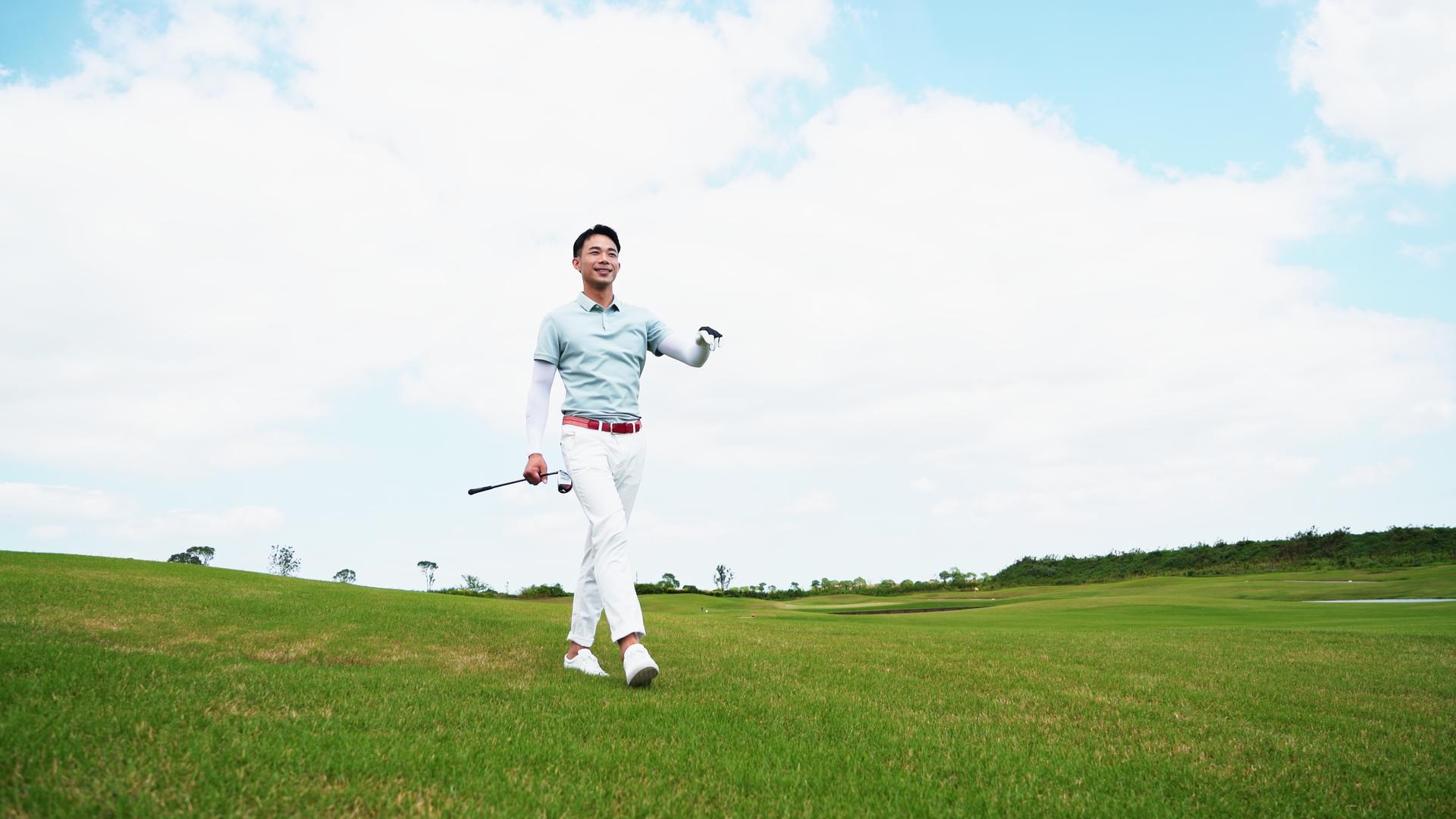 年轻男性拿着高尔夫球杆走在球场上视频的预览图