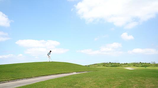 年轻男性站在坡上打高尔夫视频的预览图