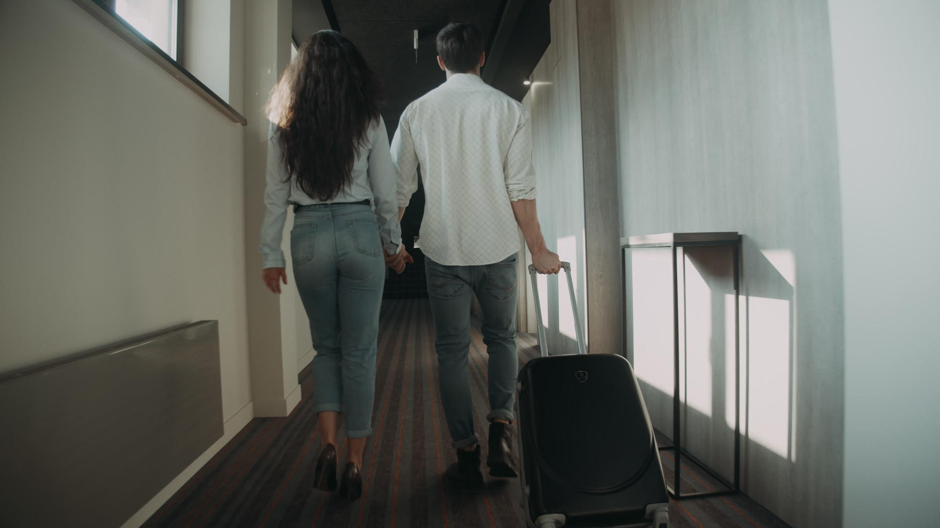 一对年轻夫妇在走廊里拉着手提箱视频的预览图