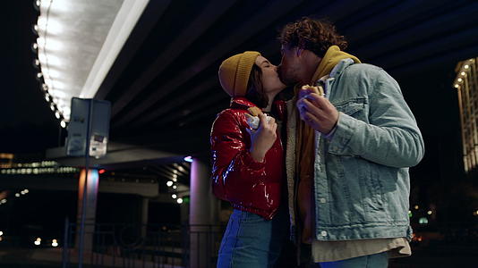 一对快乐的情侣在城市街头接吻男人和女人喜欢吃零食视频的预览图