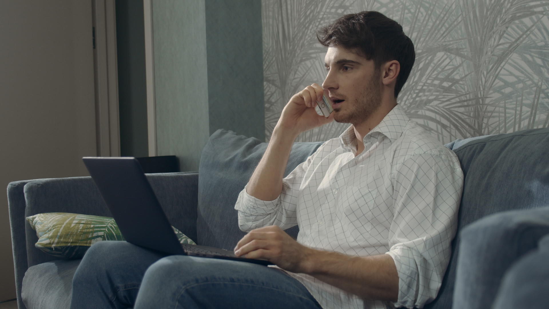 男子一边打电话一边使用笔记本电脑视频的预览图