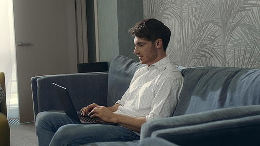 男士在酒店房间里用笔记本电脑笑视频的预览图