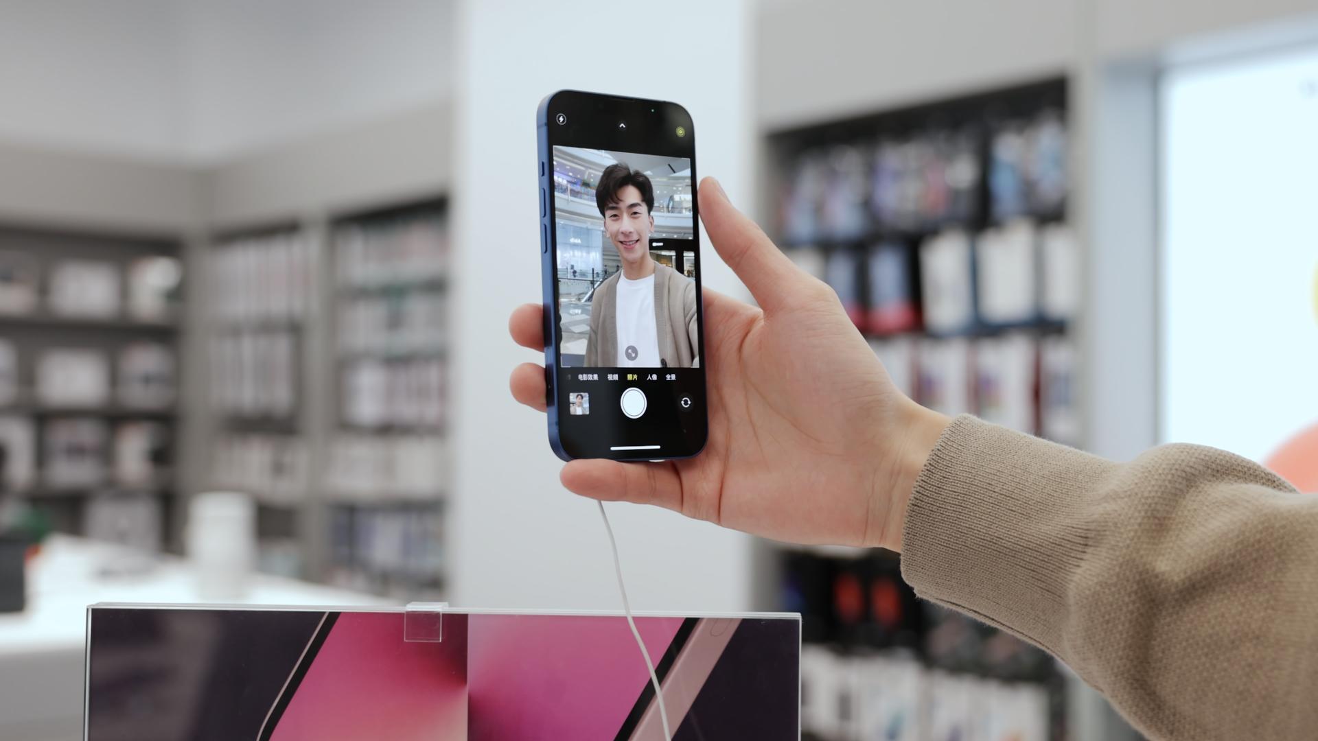 年轻男性数码店体验手机自拍功能视频的预览图