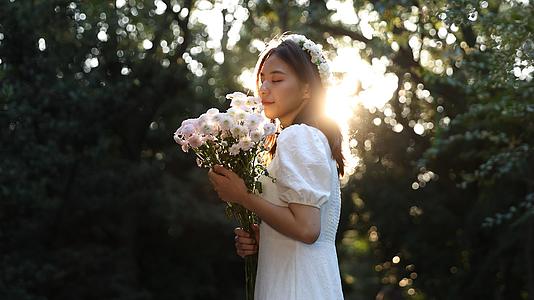 女生手捧鲜花享受自然与落日阳光视频的预览图