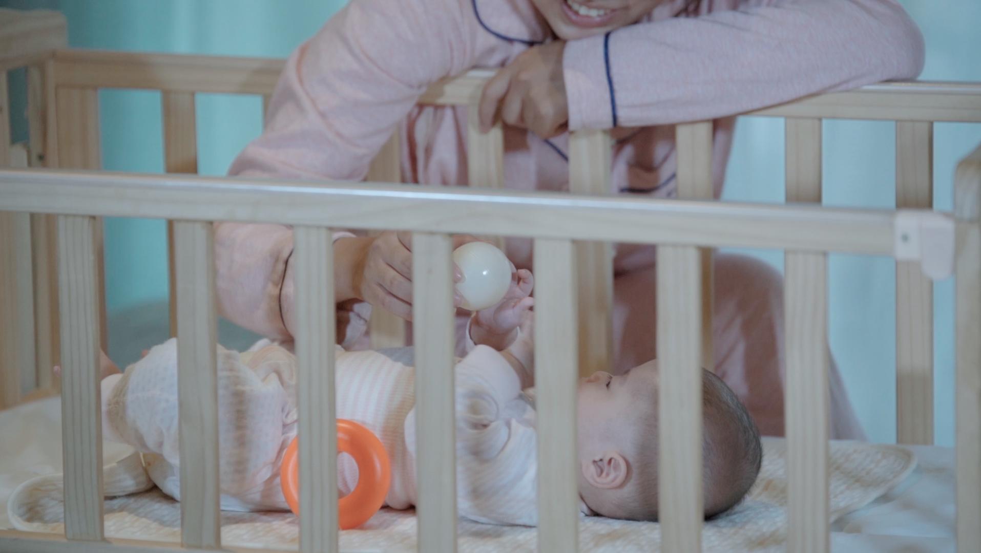 4k升格宝宝在婴儿床里和妈妈互动玩玩具特写视频的预览图
