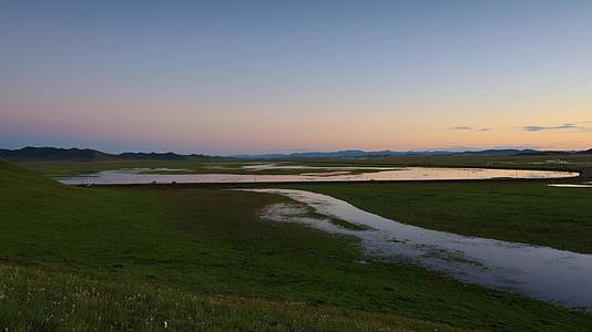 草原日落与蜿蜒河流延时视频视频的预览图