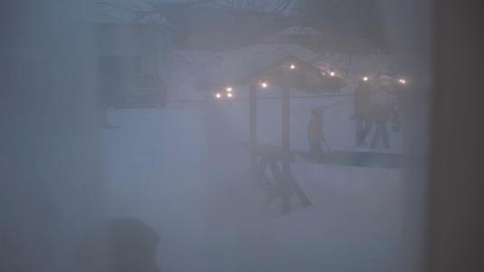 寒冬傍晚黄昏隔着窗帘拍摄户外家庭亲子雪地曲棍球游戏视频的预览图