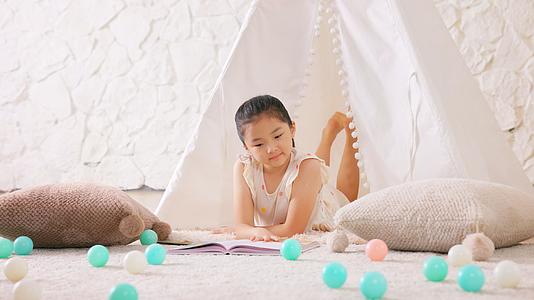 小女孩趴在毯子上悠闲看书视频的预览图