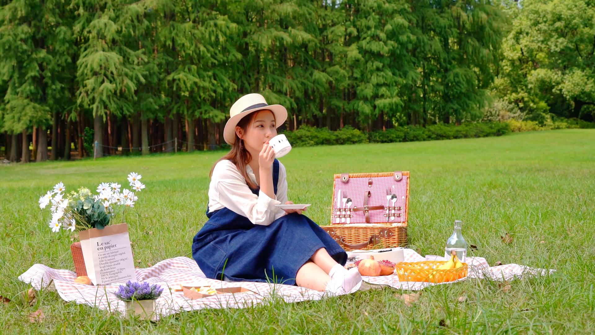 草地上野餐喝咖啡的女青年视频的预览图