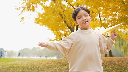 4K秋季公园小男孩在银杏树下扔纸飞机视频的预览图