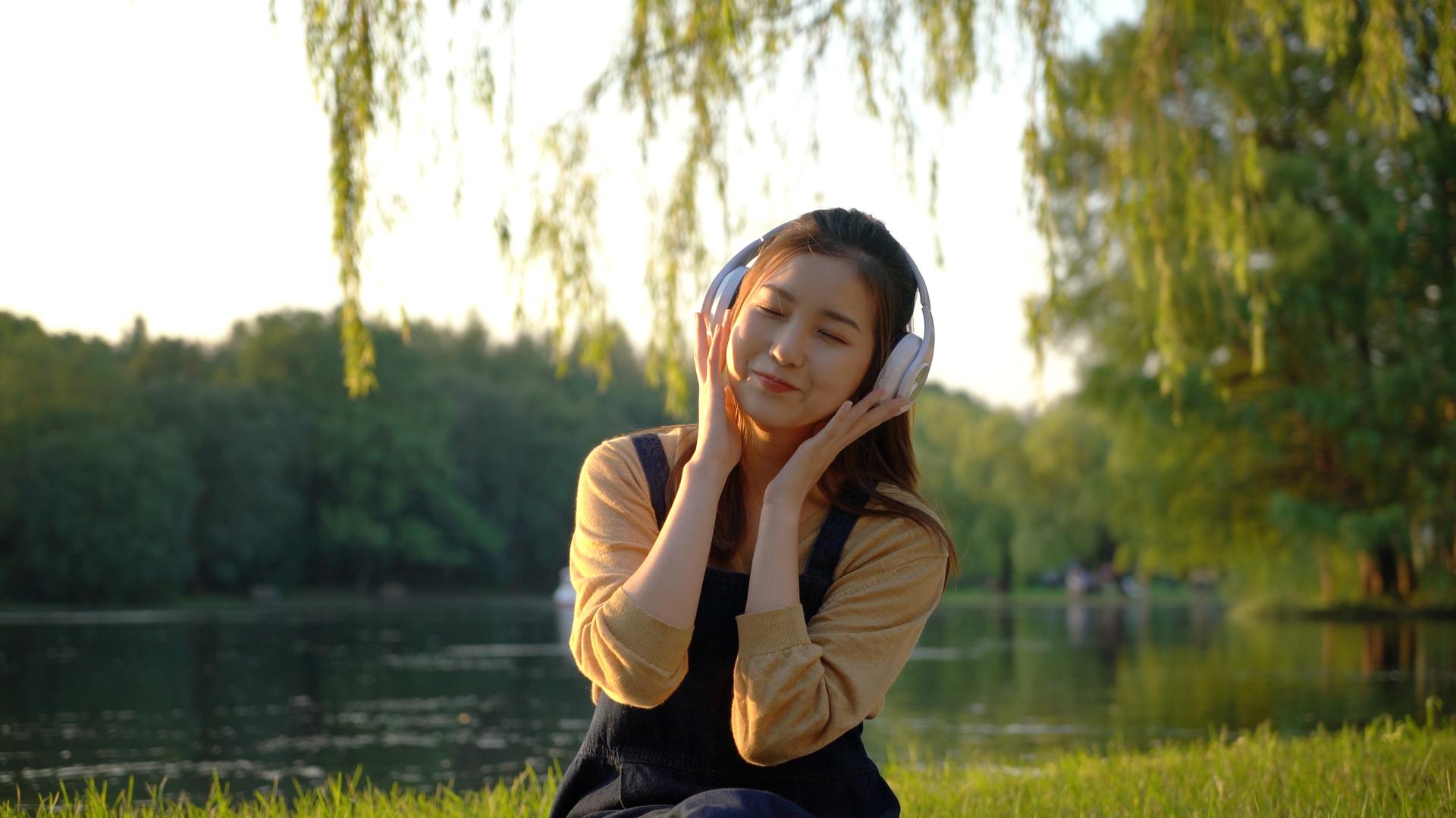 户外河边听音乐的女青年视频的预览图