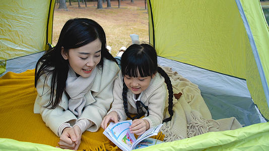 妈妈陪小女孩在帐篷中看故事书视频的预览图