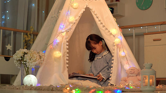 可爱小女孩坐在迷你帐篷里看书视频的预览图
