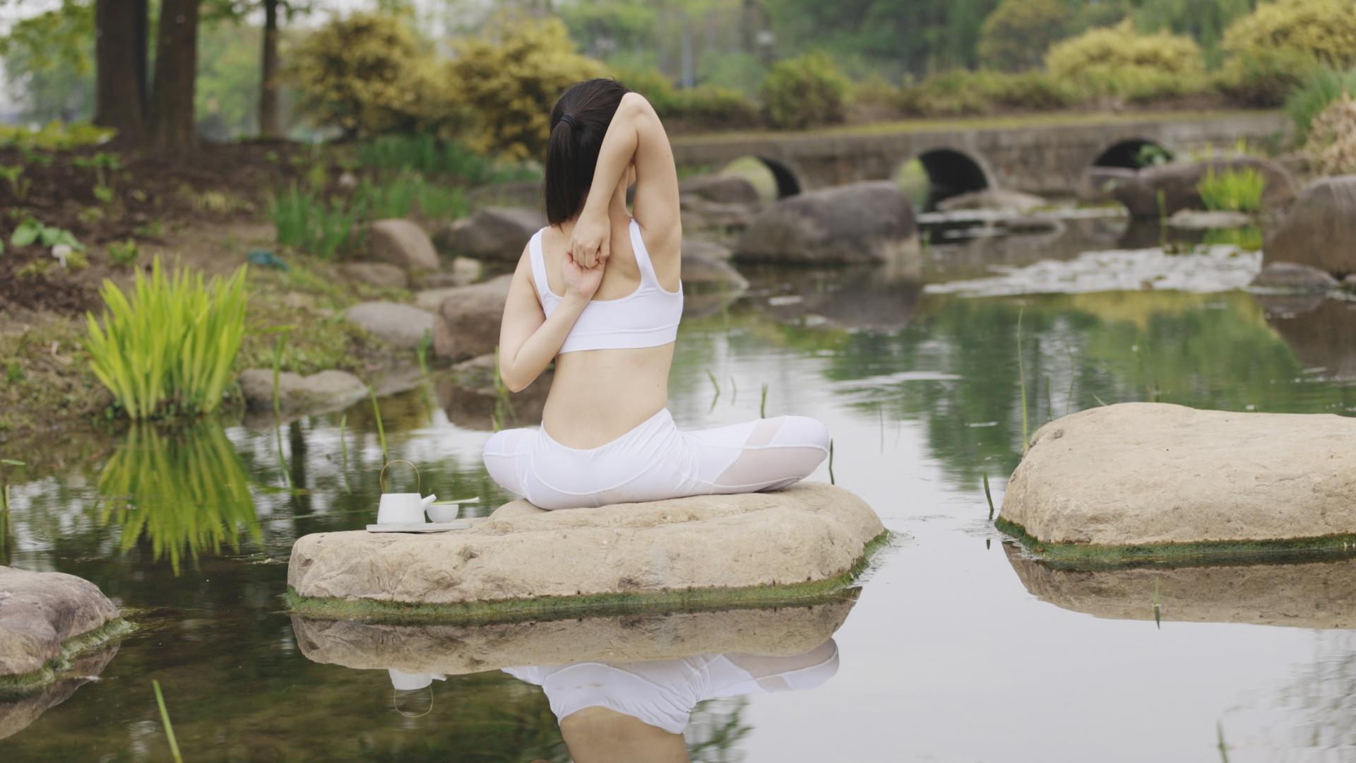 瑜伽女生坐在石头上做拉伸视频的预览图