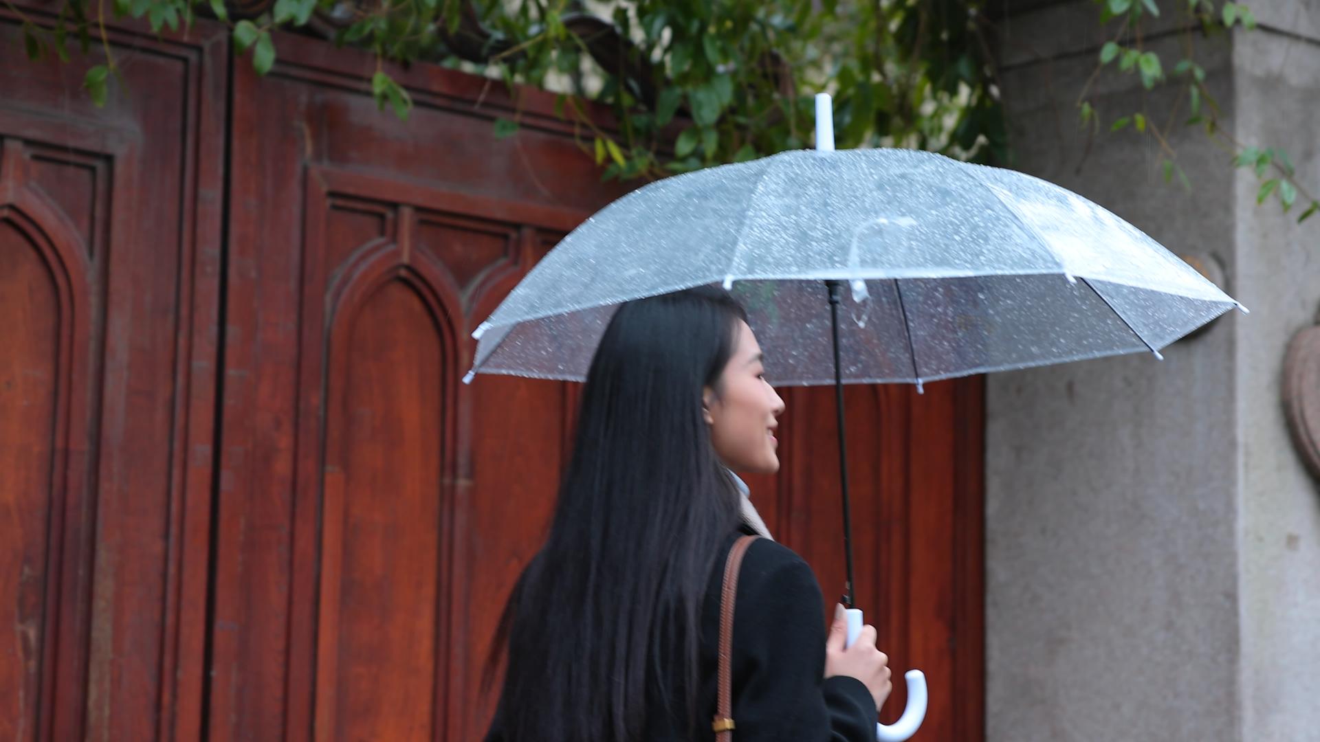 女人在雨中撑着伞走在后面视频的预览图