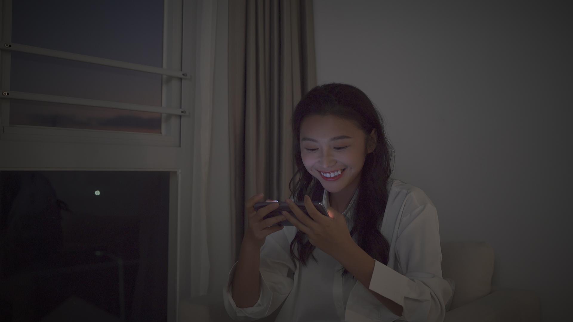 4k女性夜晚坐在窗边打手机游戏素材模板下载 版权视频可商用 潮点视频