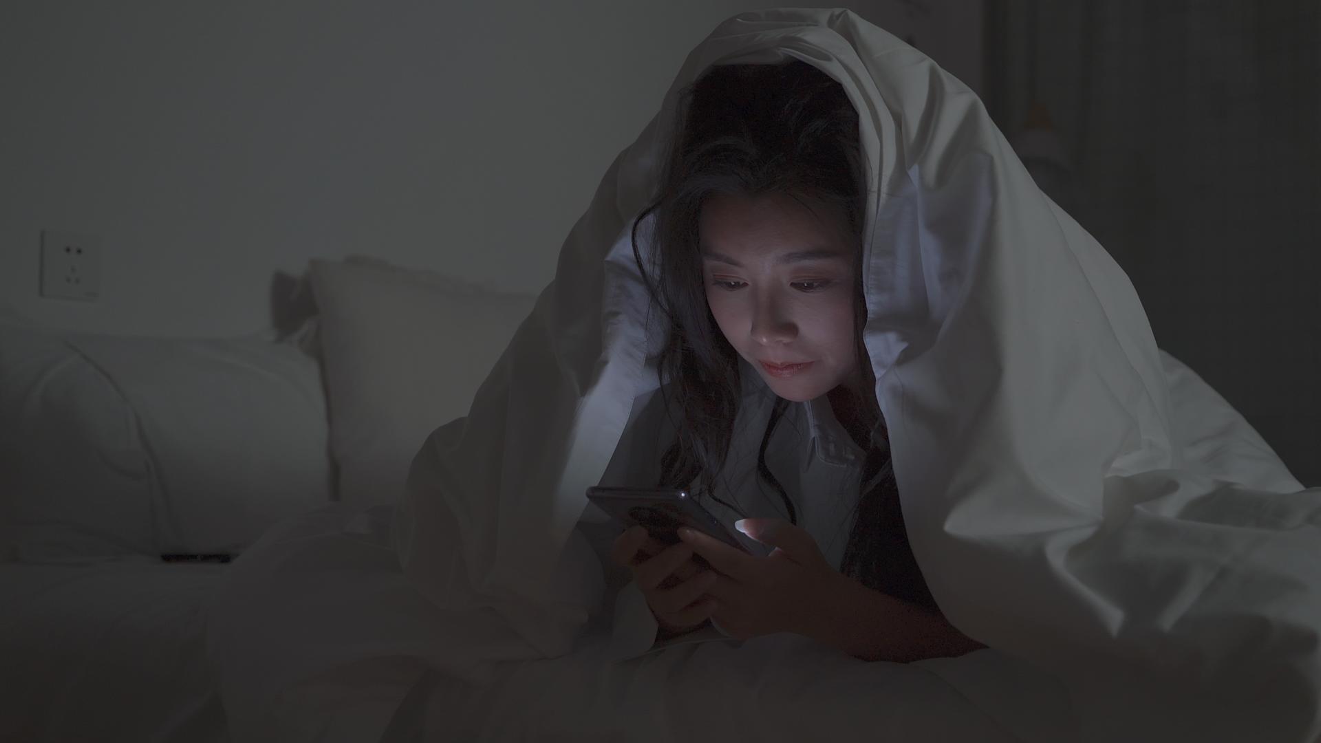 4K女性在被子里熬夜玩手机视频的预览图