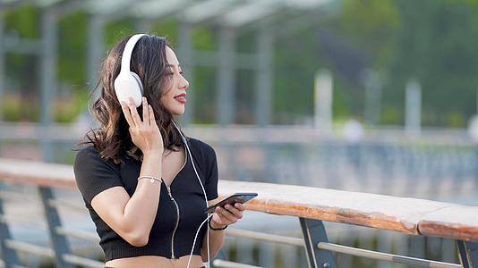 4k户外时尚女性戴耳机听音乐视频的预览图
